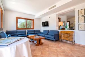 a living room with blue couches and a table at Villa Olivetta con piscina in Alghero