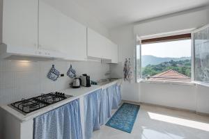 a white kitchen with a stove and a window at Villino Chiara in Pannesi