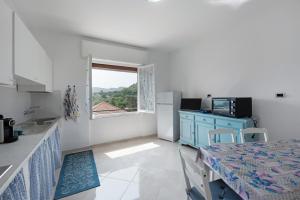 a kitchen with a table and a blue cabinet and a window at Villino Chiara in Pannesi +21 photos