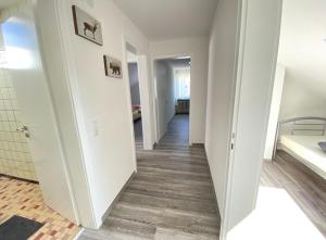 a hallway with white walls and wooden floors at Haus Schwarzwald - Bad Krozingen in Bad Krozingen
