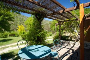 a patio with a table and chairs under a wooden pergola at Les Planious in LʼÉpine