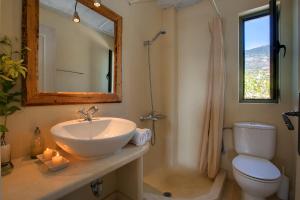 a bathroom with a sink and a toilet and a mirror at Villa Mataki Ideales Resort in Kefallonia +9 photos