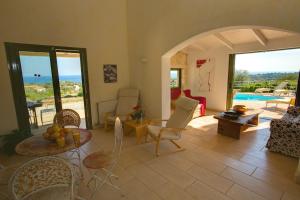 a living room with a table and chairs and a pool at Villa Mataki Ideales Resort in Kefallonia
