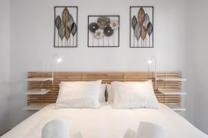 a bedroom with a white bed with four pictures on the wall at Experiencia Marina A107 in Torrox +25 photos