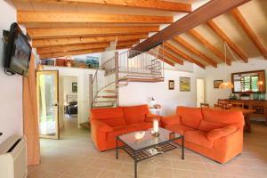 a living room with orange furniture and a spiral staircase at Ca Na Barbara in Santanyi