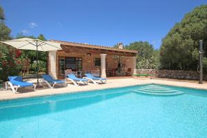 a swimming pool with chairs and an umbrella next to a house at Ca Na Barbara in Santanyi