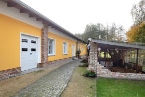 a house with yellow walls and a stone driveway at Ferienwohnung Müncheberg 2 in Müncheberg