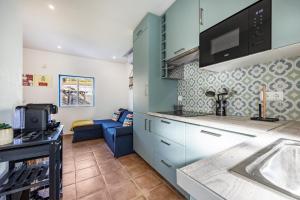 a kitchen with blue cabinets and a blue couch at Salema Beach House in Salema