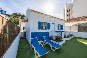a balcony with two blue chairs and a fence at Salema Beach House in Salema