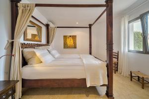 a bedroom with a canopy bed with white sheets and pillows at Casa Delfin in Moraira +29 photos