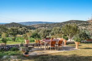 a table and chairs in a garden with mountains in the background at Zoi apartment in Kefallonia