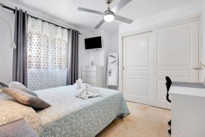 a white bedroom with a bed and a ceiling fan at Sol y Mar Caleta de Fuste in Caleta De Fuste +17 photos