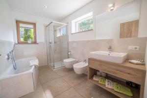 a bathroom with a tub and a sink and a toilet at Gasserhof - Chalet B in Meltina +17 photos