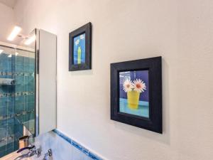 a bathroom with two pictures of a vase with a flower in it at Villa Galatea La Conchiglia in Capoliveri +29 photos