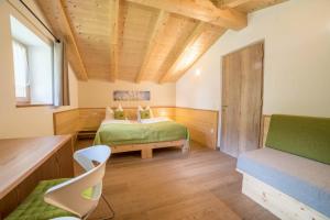 a bedroom with two beds and a bench in a room at Gasserhof - Chalet B in Meltina