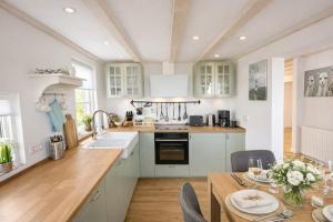 a kitchen with white cabinets and a table with a dining room at Ferienhaus 'Huus ant Diek mit Pool' in Norden