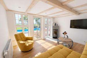 a living room with a couch and chairs and a tv at Ferienhaus 'Huus ant Diek mit Pool' in Norden