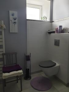a bathroom with a toilet and a chair and a window at Chambre Chanteloup in Mont-Dol