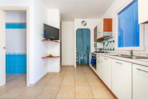 a kitchen with white cabinets and a tv on the wall at Sottotorre 1 in Calasetta +19 photos