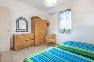 a bedroom with two beds and a dresser and a window at Sottotorre 1 in Calasetta