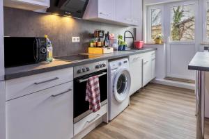 a kitchen with white cabinets and a washer and dryer at Traumwohnung Radolfzell am Bodensee in Radolfzell am Bodensee
