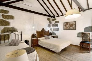 a bedroom with two beds and a stone wall at La casa nueva in Fátaga