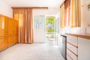 a kitchen with white cabinets and a large window at Panorama Tilos Apt B in Tílos