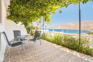a table and chairs on a patio with a view of the beach at Panorama Tilos Apt B in Tílos +4 photos