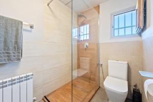 a bathroom with a toilet and a glass shower at Habitacion Doble Jardin in Camarles