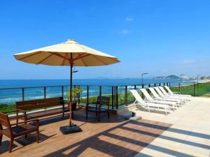 a patio with chairs and an umbrella and the ocean at Resort com vista mar! in Barra Velha