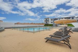 a row of lounge chairs with umbrellas and a pool at vv Sueño Del Mar in Costa de Antigua