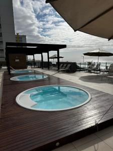two swimming pools on top of a deck with the ocean at Resort com vista mar! in Barra Velha