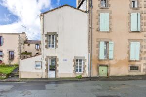 a white building with a green door on a street at Le Clemenceau in Les Épesses