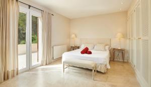 a bedroom with a white bed with a red pillow on it at Can Pascalou in Canyamel +21 photos