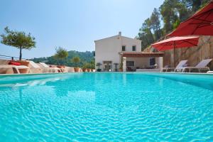 a large swimming pool with a red umbrella and chairs at Can Pascalou in Canyamel