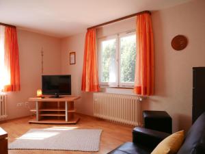 a living room with orange curtains and a tv at Börsighof in Seebach