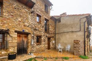 an old stone building with two chairs and a table at Masía La Parreta in Villafranca del Cid