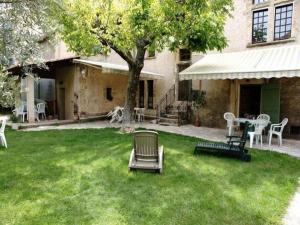 a yard with chairs and a table and a tree at Gîte Clarisse, piscine, animaux, pk in Allemagne-en-Provence