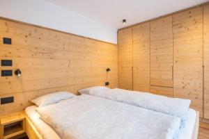 two beds in a room with wooden walls at Apartments Armeri Black Dolomites in San Vigilio Di Marebbe