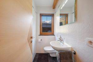 a bathroom with a toilet and a sink and a window at Sprenghof Ferienwohnung in Sarntal +28 photos
