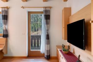 a living room with a flat screen tv and a window at Sprenghof Ferienwohnung in Sarntal