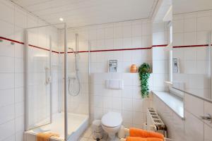 a white bathroom with a shower and a toilet at Huus Meernmank in Achtrup +25 photos