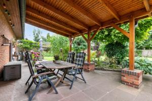 a patio with a wooden pergola and a table and chairs at Ferienhaus Dohle in Vollerwiek