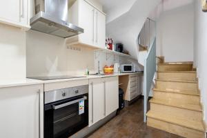 eine kleine Küche mit weißen Schränken und eine Treppe in der Unterkunft Vendrell Centre in El Vendrell + 12 Fotos