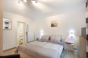 a white bedroom with a bed and a mirror at Lausebuche Im Sauerland in Lennestadt