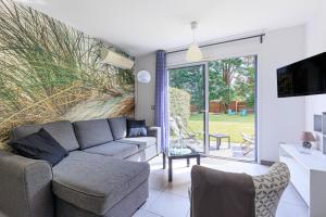 a living room with a couch and a tv at Maison La Dune, Piscine et Jardin in Messanges