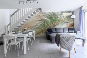 a living room with a couch and a table and chairs at Maison La Dune, Piscine et Jardin in Messanges