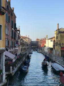 um canal entre dois edifícios com barcos na água em Casa Burchielle em Veneza