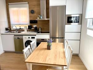 a kitchen with a wooden table and a stainless steel refrigerator at La Coqueta in Zarandona