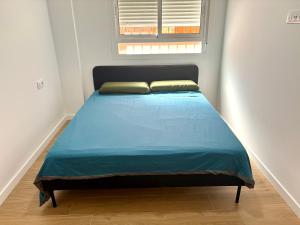a bedroom with a bed with a blue comforter and a window at La Coqueta in Zarandona